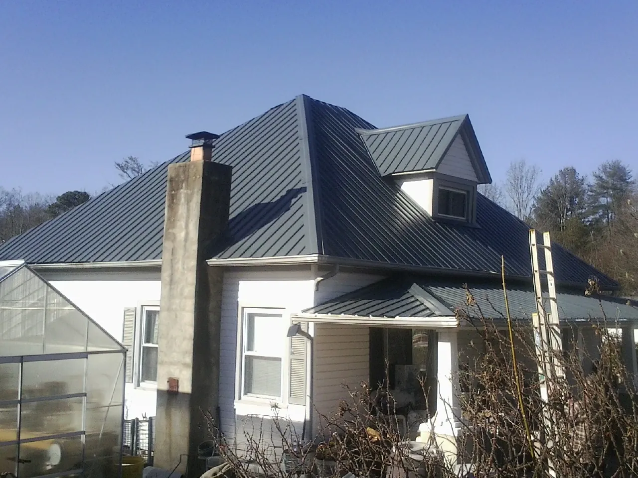 Dark blue standing seam metal roof on a white farmhouse with dormer — Slate & Tile Roof Repair by Roofing Brothers in Beech Creek