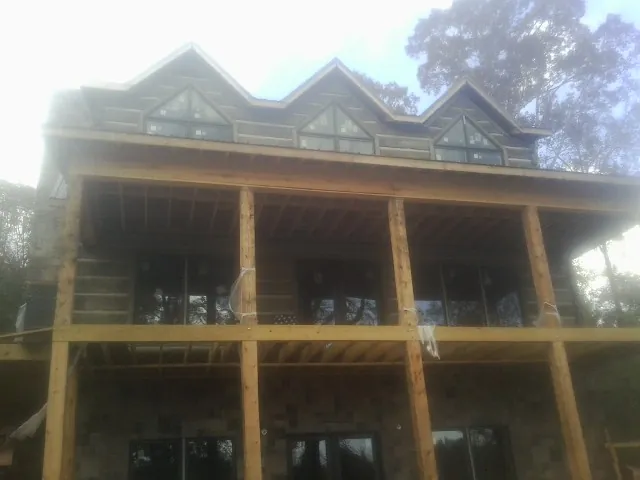 Dormers and porch framing on a large log home under construction — Roof Coating work by our crew in Beech Creek