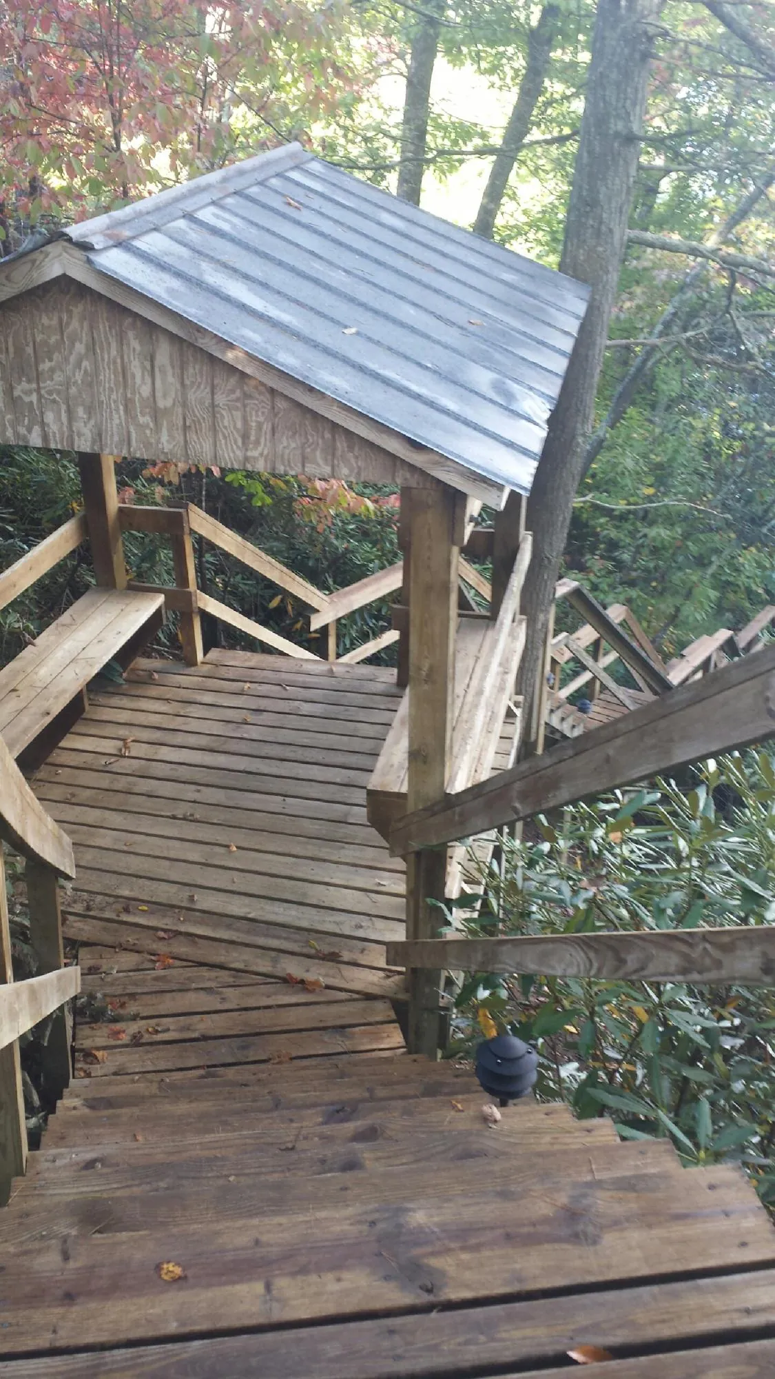 Metal roofed shelter over wooden steps on a wooded walkway — Skylight Repair & Installation work by our crew in Beech Creek