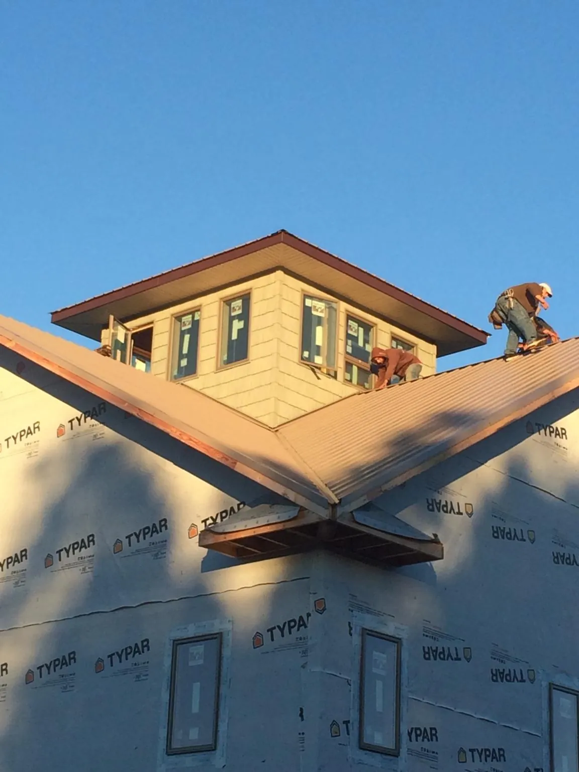 Roofers working around a rooftop cupola on a new metal roof at sunset — Roof Waterproofing in Beech Creek by Roofing Brothers